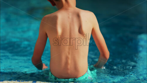 Overhead shot of a young boy playing in a bright blue swimming pool - Starpik Stock