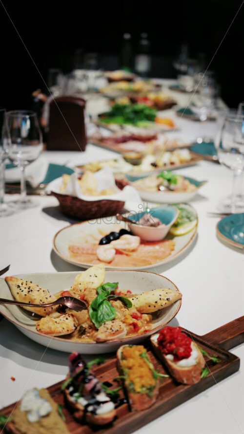 Overhead view of a restaurant table filled with gourmet appetizers, bread, seafood, and salads. Vertical - Starpik Stock