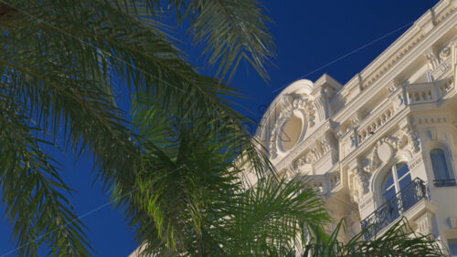 Palm trees swaying beneath a bright sky and a building in the south of France - Starpik Stock