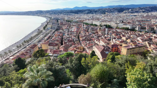 Panoramic aerial view of Nice, France, showcasing the Promenade des Anglais, the beach, and the old town with its iconic red rooftops - Starpik Stock