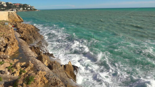 Powerful waves crashing against a rocky Mediterranean coastline - Starpik Stock
