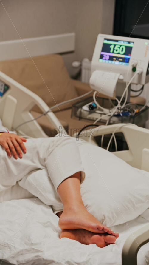 Pregnant woman lying in a hospital bed during a prenatal check-up at the doctor’s office. Vertical - Starpik Stock