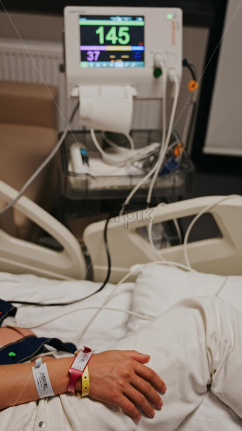 Pregnant woman lying in a hospital bed during a prenatal check-up at the doctor’s office. Vertical - Starpik Stock