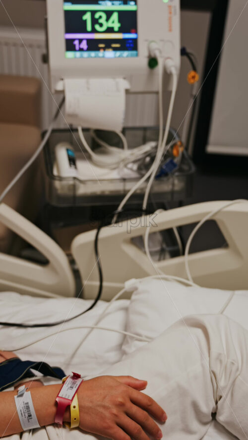 Pregnant woman lying in a hospital bed during a prenatal check-up at the doctor’s office. Vertical - Starpik Stock