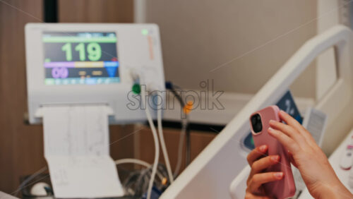 Pregnant woman scrolling on her phone while doing a prenatal check-up at the doctor’s office - Starpik Stock