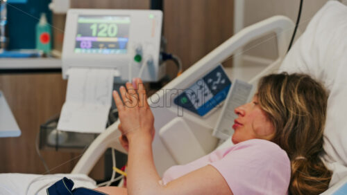 Pregnant woman scrolling on her phone while doing a prenatal check-up at the doctor’s office - Starpik Stock