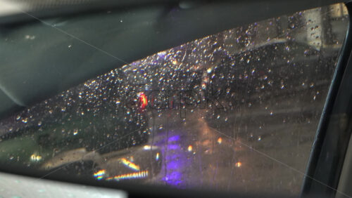 Rain dripping down the window of a moving car in the evening reflected in the rearview mirror - Starpik Stock