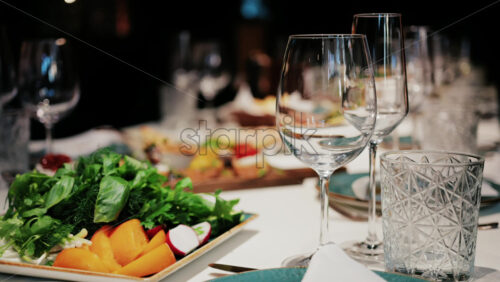 Refined restaurant table setting with crystal glasses, plates, and gourmet dishes in the background - Starpik Stock