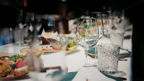 Refined restaurant table setting with crystal glasses, plates, and gourmet dishes in the background - Starpik Stock