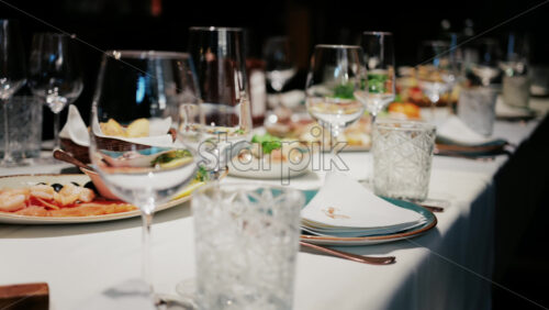 Refined restaurant table setting with crystal glasses, plates, and gourmet dishes in the background - Starpik Stock