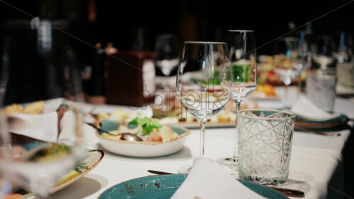 Refined restaurant table setting with crystal glasses, plates, and gourmet dishes in the background - Starpik Stock