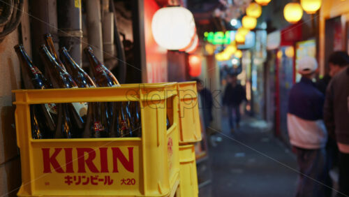 Shinjuku, Japan – April 12, 2025: Close up of a beer case with empty bottles on the side of the street with people walking on the on the Omoide Yokocho Memory Lane - Starpik Stock