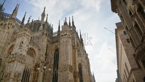 Side view of the Duomo with people walking through the square in daylight in Milan, Italy - Starpik Stock