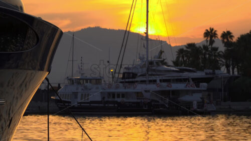 Silhouettes of sailboat masts and yachts against a golden sunset sky in the Cannes marina - Starpik Stock