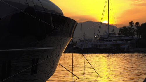 Silhouettes of sailboat masts and yachts against a golden sunset sky in the Cannes marina - Starpik Stock