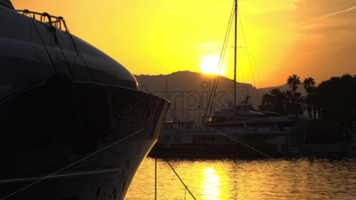 Silhouettes of sailboat masts and yachts against a golden sunset sky in the Cannes marina - Starpik Stock