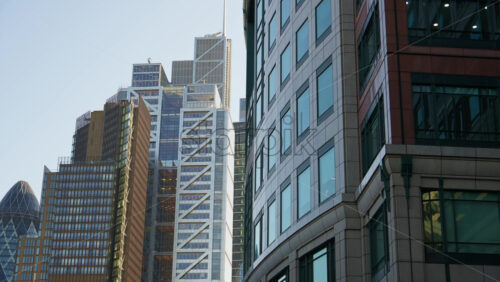 Skyline of London featuring the Gherkin, Leadenhall Building, and other modern skyscrapers under clear sky - Starpik Stock