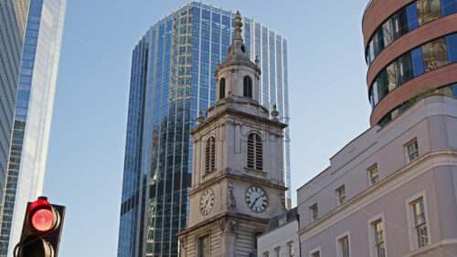 St. Botolph-without-Bishopsgate church standing prominently at the edge of Liverpool Street, framed by gleaming glass towers in London, England - Starpik Stock