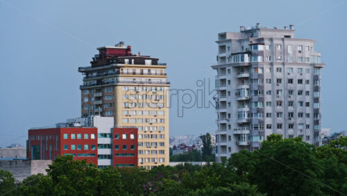 Tall buildings surrounded by green trees with the sky on the background in Chisinau, Moldova in the evening - Starpik Stock