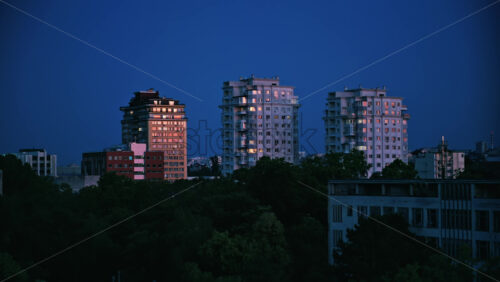 Tall buildings surrounded by green trees with the sky on the background in Chisinau, Moldova in the evening - Starpik Stock