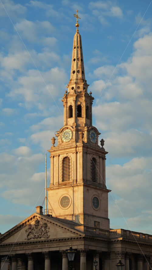 Tall clock tower of the St Martin-in-the-Fields church captured under a partly cloudy sky in London, England. Vertical - Starpik Stock