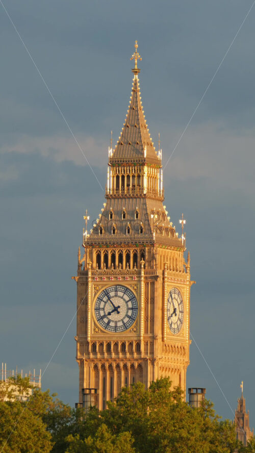 The Big Ben surrounded by green trees in the evening sunlight in London, England. Vertical - Starpik Stock