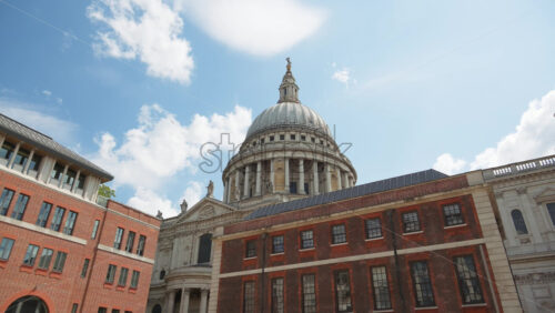 The Dome of St. Paul’s Cathedral rising above the buildings with a clear blue sky in the background in London, England - Starpik Stock