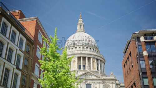 The Dome of St. Paul’s Cathedral rising above the trees with a clear blue sky in the background in London, England - Starpik Stock
