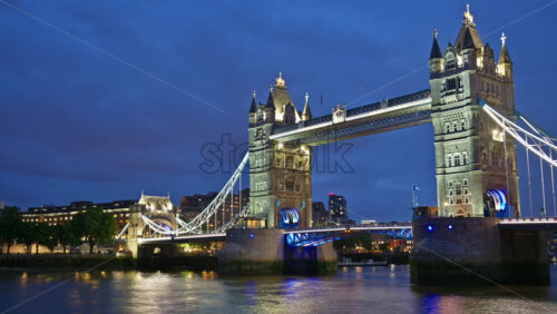 Time lapse of the Tower Bridge viewed at night with the river reflecting the lights. - Starpik Stock