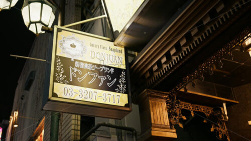 Tokyo, Japan – April 12, 2025: Gold and black lighted brothel sign on the street in Shinjuku City in the evening - Starpik Stock
