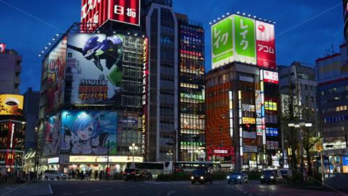 Tokyo, Japan – April 12, 2025: View of the vibrant life of Shinjuku City with people and cars moving on the streets with lighted buildings in the evening. Translation: “Kabukicho impact” - Starpik Stock