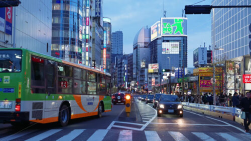 Tokyo, Japan – April 12, 2025: View of the vibrant life of Shinjuku City with people and cars moving on the streets with lighted buildings in the evening. Translation:”Company names” - Starpik Stock