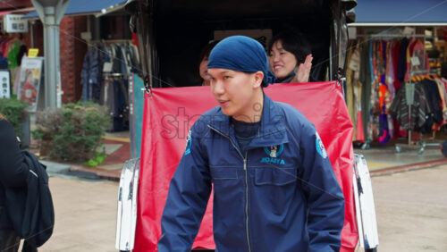 Tokyo, Japan – April 13, 2025: Two tourists riding in a rickshaw, smiling and waving near the Senso-ji temple in Asakusa - Starpik Stock