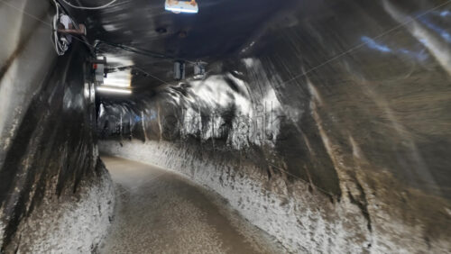 Turda, Romania – July 20, 2025: A narrow, illuminated tunnel inside the Turda Salt Mine with directional signage for visitors. Translation: “Direction signs and location names” - Starpik Stock