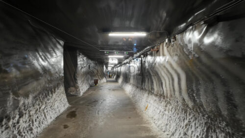 Turda, Romania – July 20, 2025: A narrow, illuminated tunnel inside the Turda Salt Mine with directional signage for visitors. Translation: “Direction signs and location names” - Starpik Stock