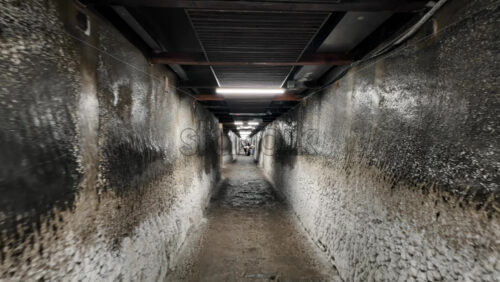 Turda, Romania – July 20, 2025: A narrow, illuminated tunnel inside the Turda Salt Mine with directional signage for visitors. Translation: “Direction signs and location names” - Starpik Stock