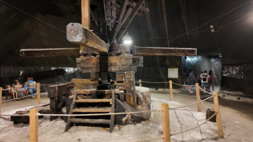 Turda, Romania – July 20, 2025: Large wooden extraction machinery displayed inside the Turda salt mine, with tourists walking around - Starpik Stock