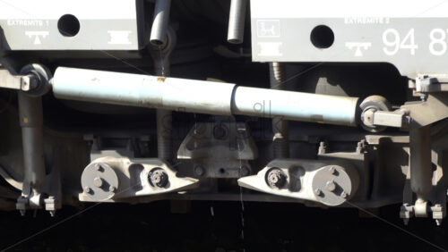 Vallauris, France – July 6, 2025: Close up of a train’s undercarriage suspension system, with droplets of water falling from the hydraulic components - Starpik Stock