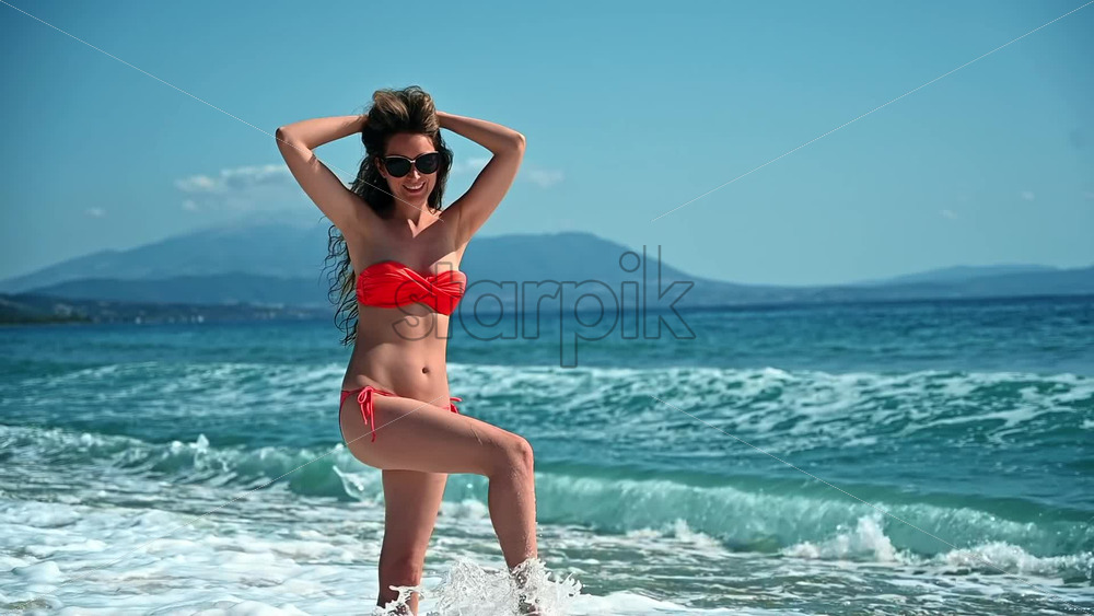 Video – A woman enjoying her vacation on the beach by the Mediterranean sea, dancing in the water in slow motion - Starpik Stock