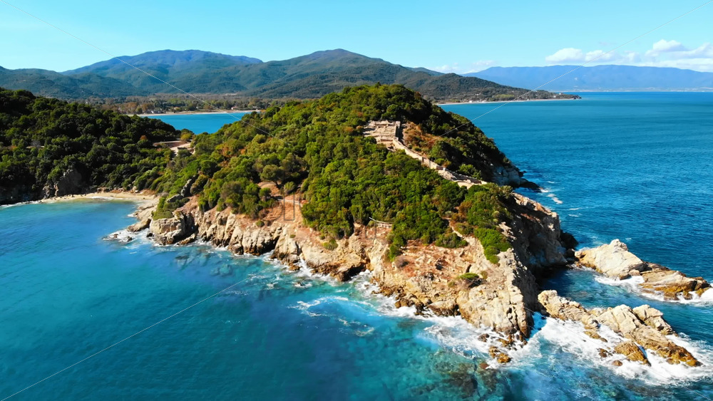 Video – Aerial drone view of the Aegean sea rocky coast, peninsula with greenery and ancient excavations on the hill, waves with a lot of foam, Greece - Starpik Stock