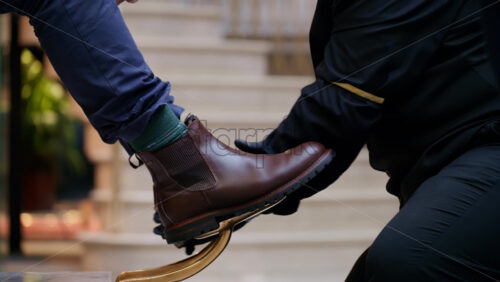 Video – Close-up of a brown leather boot being polished by a shoeshiner wearing black gloves on a vintage shoe shine stand in London, England - Starpik Stock
