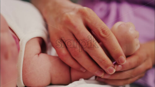 Video – Close up of a parent’s hands massaging a baby’s hands and arms - Starpik Stock