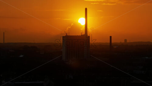 Video – Copenhagen, Denmark – August 3, 2025: Aerial drone view of the city’s skyline during sunset, with the sun glowing above landmarks and industrial chimneys silhouetted against the orange sky - Starpik Stock