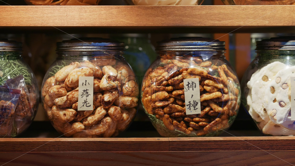 Video - Kyoto, Japan - April 11, 2025: Close up of seed jars for sale at the Asakusa, Kannon Dori Market. Translation: "Small falling flowers, persimmon seeds"