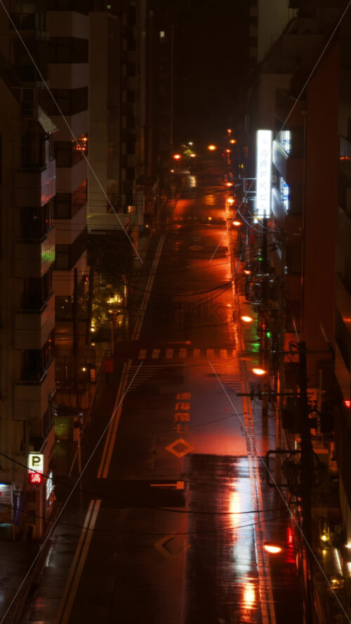 Video - Kyoto, Japan - April 11, 2025: High angle view of an empty street in Tokyo, Japan, on a rainy evening with orange lights. Vertical