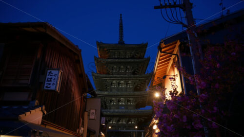Video - Kyoto, Japan - April 11, 2025: View of the Yasaka Shrine from the Ninenzaka street in the evening. Translation: "Yasaka Tobacco Kiosk"