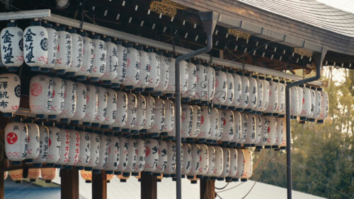Video - Kyoto, Japan - April 11, 2025: White paper lanterns hanging at the Yasaka Shrine at sunset. Translation: "Names of local businesses and donors"