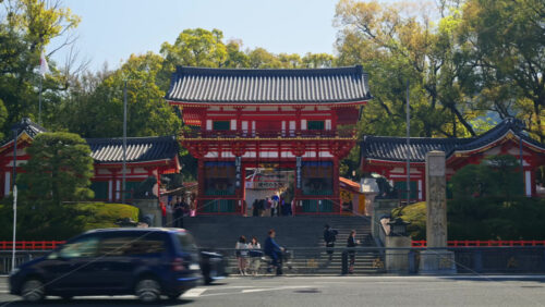 Video - Kyoto, Japan - April 12, 2025: Distant view of people moving on the stairs at the Yasaka Jinja Nishiromon Gate at the Shinto shrine. Translation: "Tsutsuji festival"