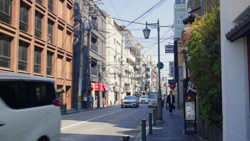 Video - Kyoto, Japan - April 12, 2025: People and cars moving on the streets of the Gion area in daylight. Translation: "Street and store names"
