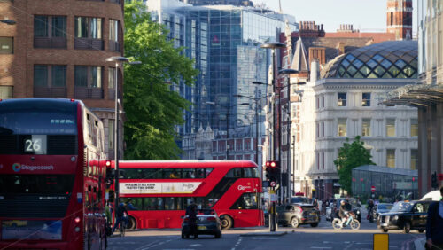 Video – London, England – May 13, 2025: Multiple red double-decker buses and cars filling the busy Bishopsgate street as cyclists and pedestrians move on the streets - Starpik Stock